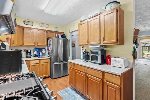 1261 Lipps Ln, Louisville, KY 40219 - kitchen featuring stainless steel appliances, a textured ceiling, light countertops, and light wood-type flooring