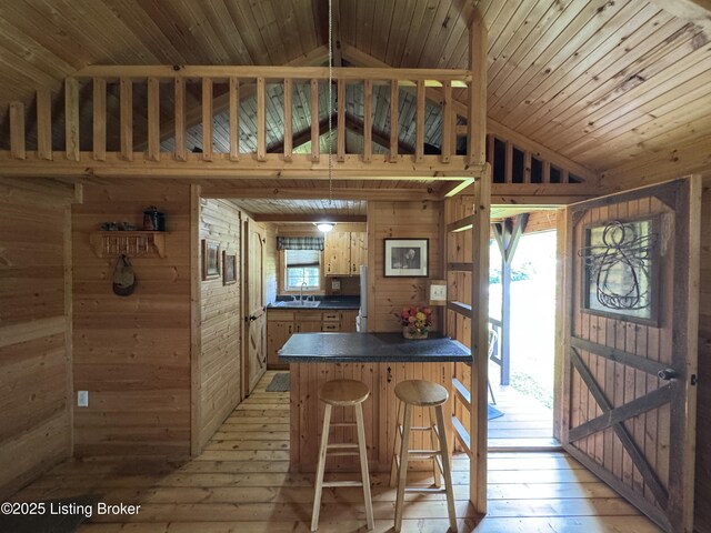 661 Blue Bird Rd, Falls Of Rough, KY 40119 - kitchen featuring wood walls, lofted ceiling, dark countertops, light wood-style floors, and a peninsula
