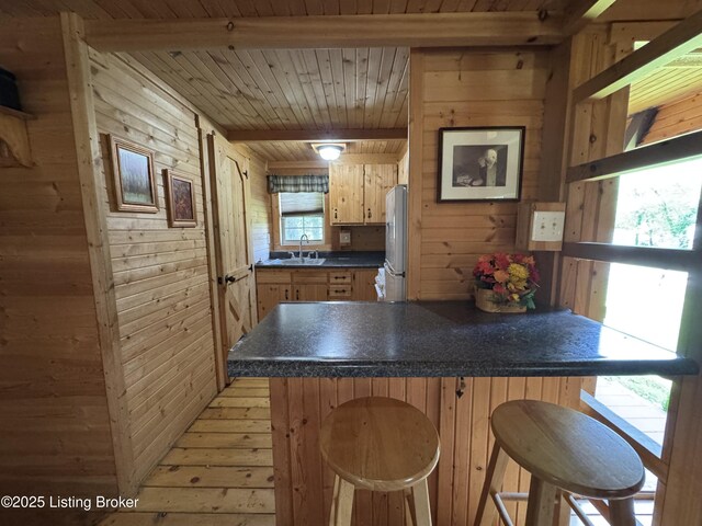 661 Blue Bird Rd, Falls Of Rough, KY 40119 - kitchen featuring freestanding refrigerator, wooden walls, wooden ceiling with exposed beams, a peninsula, and dark countertops