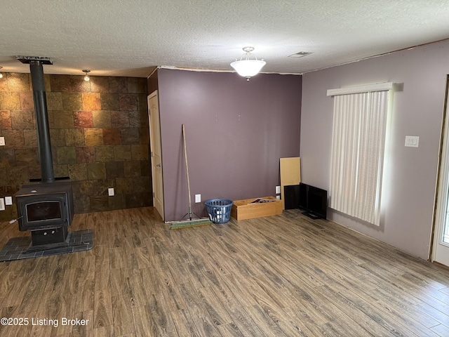 775 Constantine Vertrees Rd, Garfield, KY 40140 - unfurnished living room featuring wood finished floors, a textured ceiling, and a wood stove