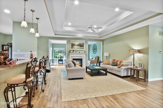 4107 Dolphin Rd, Louisville, KY 40220 - living room with a tray ceiling, ornamental molding, wood finished floors, a glass covered fireplace, and a ceiling fan