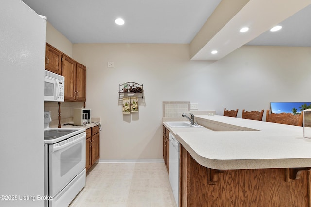 4107 Dolphin Rd, Louisville, KY 40220 - kitchen with white appliances, a breakfast bar, a peninsula, baseboards, and recessed lighting