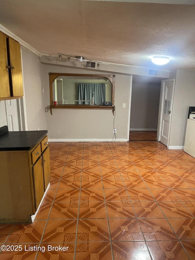 1207 Doris Dr, Fairdale, KY 40118 - kitchen featuring a textured ceiling, dark countertops, baseboards, and brown cabinets