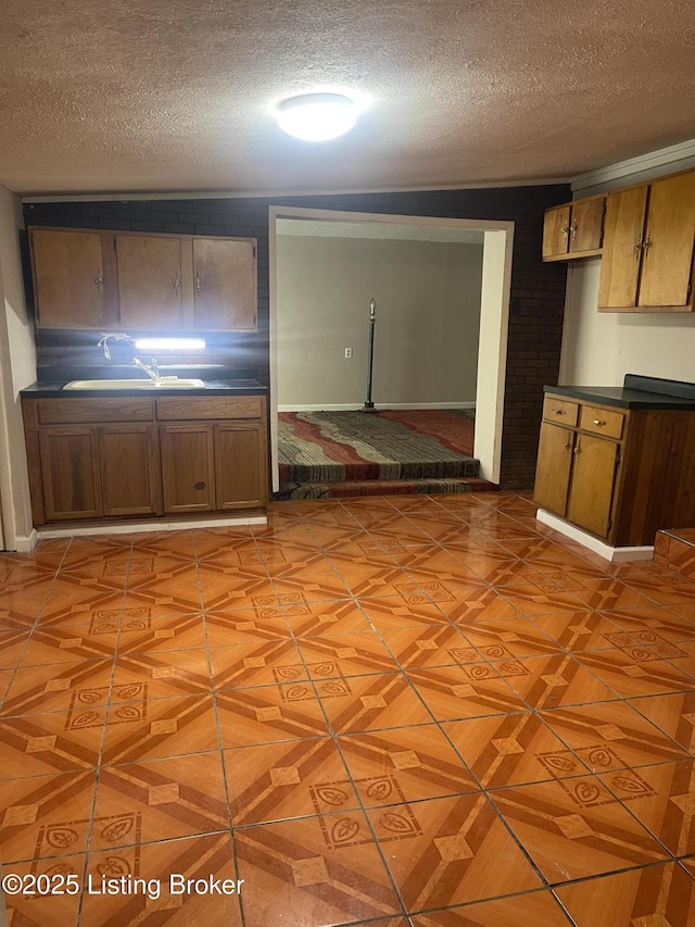 1207 Doris Dr, Fairdale, KY 40118 - kitchen featuring a sink, a textured ceiling, dark countertops, and brown cabinetry