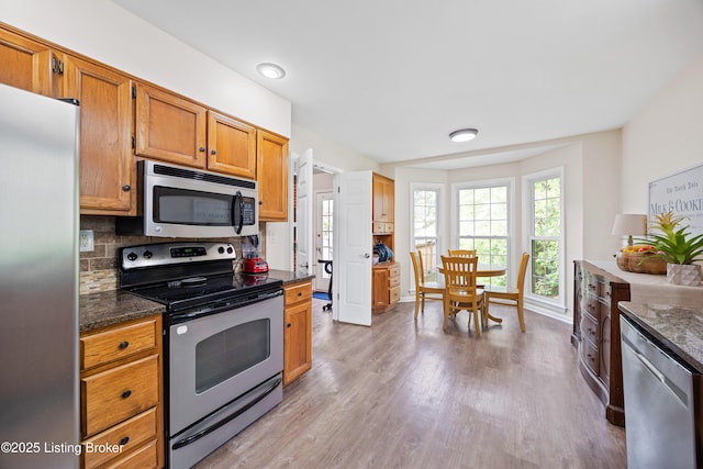 14312 Micawber Way, Louisville, KY 40245 - kitchen featuring appliances with stainless steel finishes, light wood-type flooring, backsplash, dark stone counters, and baseboards