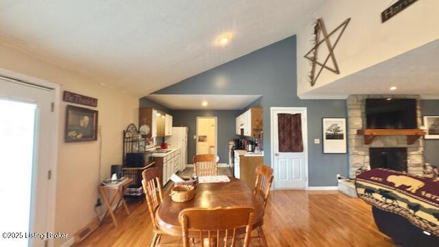 187 Glenn Rd, Leitchfield, KY 42754 - dining space featuring high vaulted ceiling, a stone fireplace, baseboards, and light wood finished floors