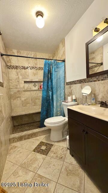 187 Glenn Rd, Leitchfield, KY 42754 - bathroom with tile walls, toilet, vanity, tiled shower, and tile patterned flooring