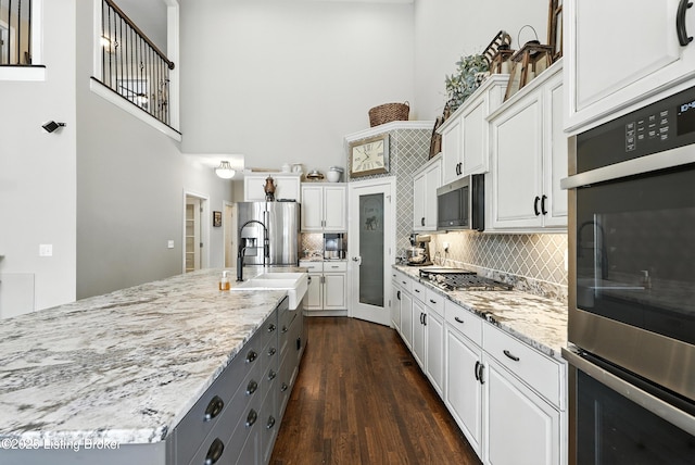 13127 Wilhoyte Ct Unit 13127, Prospect, KY 40059 - kitchen with a high ceiling, white cabinets, stainless steel appliances, dark wood-type flooring, and tasteful backsplash