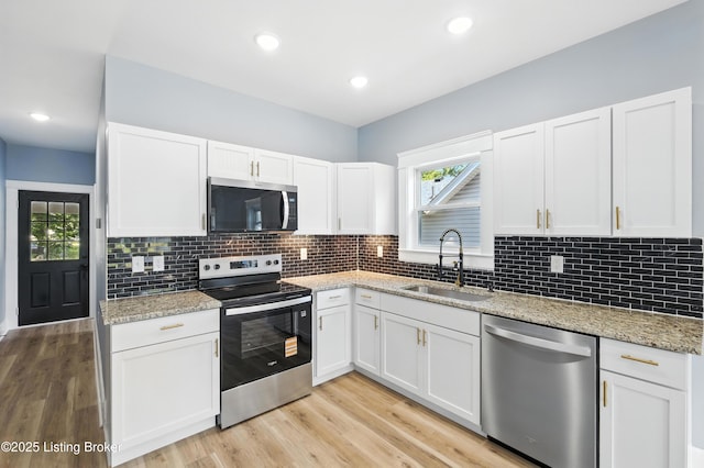 220 N 39th St, Louisville, KY 40212 - kitchen with stainless steel appliances, white cabinetry, decorative backsplash, light wood-type flooring, and light stone countertops