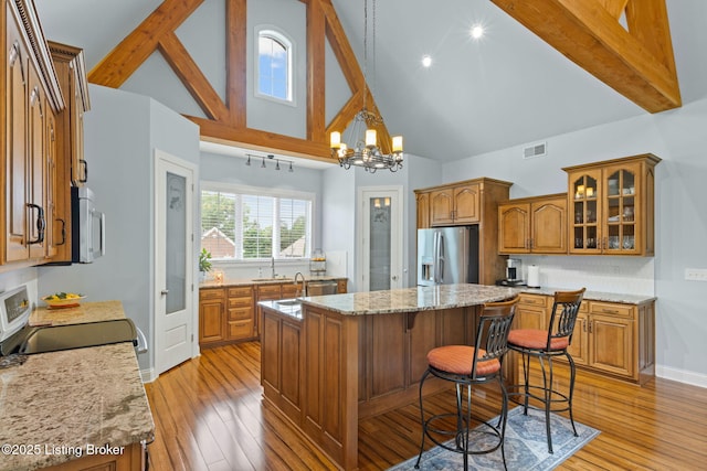4225 Pleasant Glen Dr, Louisville, KY 40299 - kitchen featuring stainless steel appliances, brown cabinets, a center island, high vaulted ceiling, and a sink