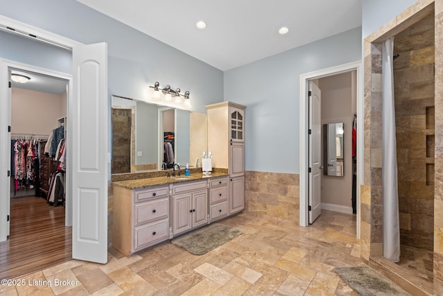 4225 Pleasant Glen Dr, Louisville, KY 40299 - bathroom with a walk in closet, vanity, tiled shower, a wainscoted wall, and stone tile floors