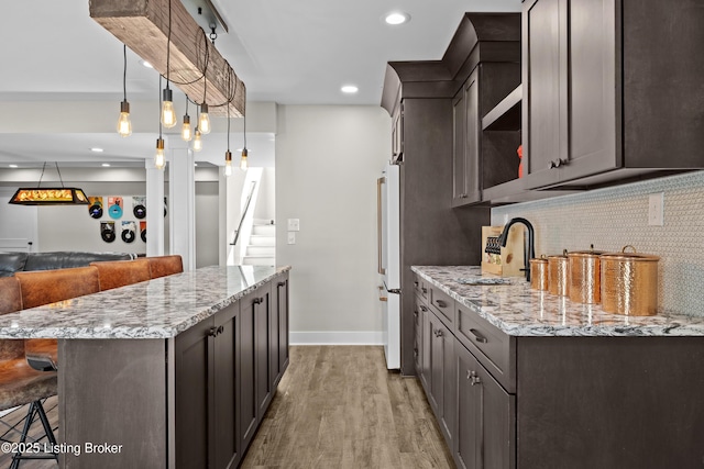 5404 River Creek Ct, Prospect, KY 40059 - kitchen with wood finished floors, tasteful backsplash, a center island, dark brown cabinets, and a breakfast bar