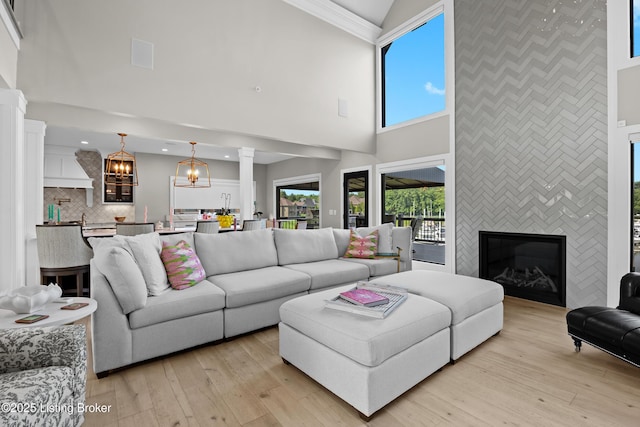 5404 River Creek Ct, Prospect, KY 40059 - living room featuring high vaulted ceiling, ornate columns, light wood-type flooring, a chandelier, and an accent wall