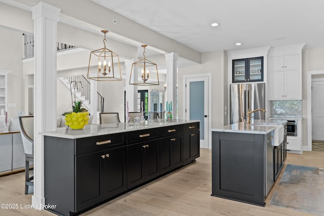 5404 River Creek Ct, Prospect, KY 40059 - kitchen featuring dark cabinets, freestanding refrigerator, a spacious island, ornate columns, and white cabinets