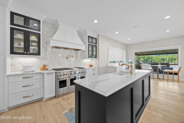 5404 River Creek Ct, Prospect, KY 40059 - kitchen featuring range with two ovens, custom range hood, tasteful backsplash, light wood finished floors, and light stone countertops