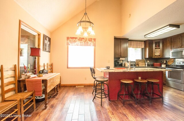 52 Lakeshore Cir, Leitchfield, KY 42754 - kitchen with appliances with stainless steel finishes, a breakfast bar area, wood finished floors, an island with sink, and high vaulted ceiling
