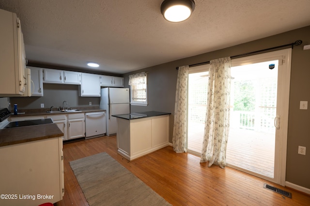 7215 Applegate Ln, Louisville, KY 40228 - kitchen with white appliances, a sink, dark countertops, light wood-style flooring, and a textured ceiling