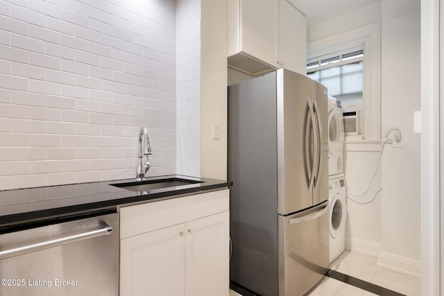1412 Willow Ave Unit 56, Louisville, KY 40204 - kitchen with appliances with stainless steel finishes, stacked washer / drying machine, decorative backsplash, dark countertops, and white cabinetry
