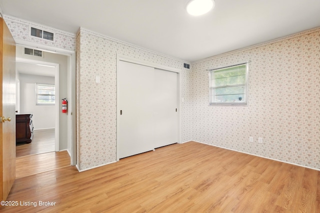 1212 Hibiscus Dr, Clarksville, IN 47129 - unfurnished bedroom featuring light wood finished floors, wallpapered walls, a closet, and ornamental molding