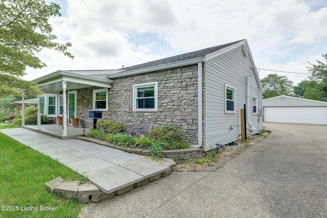 3116 Osprey Rd, Louisville, KY 40213 - view of front of home with covered porch, stone siding, an outbuilding, and a garage
