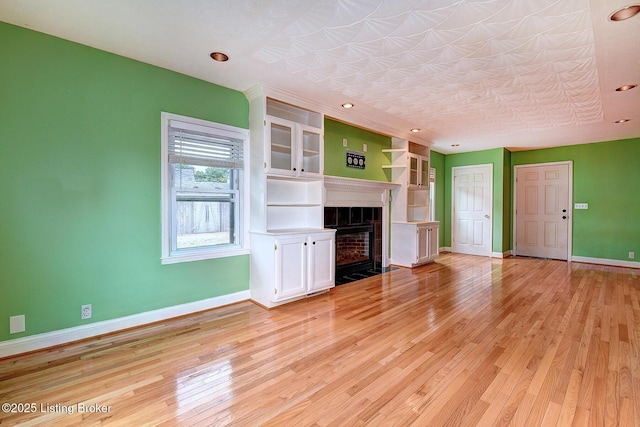 3116 Osprey Rd, Louisville, KY 40213 - unfurnished living room with light wood-type flooring, a tiled fireplace, and recessed lighting