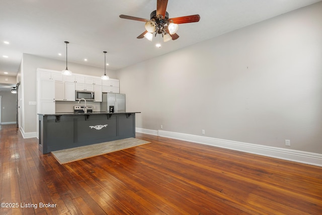 948 Samuel St, Louisville, KY 40204 - kitchen with appliances with stainless steel finishes, ceiling fan, dark countertops, white cabinetry, and a kitchen breakfast bar