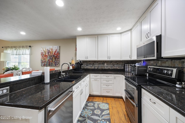 12582 Springfalls Ct, Louisville, KY 40229 - kitchen with appliances with stainless steel finishes, a peninsula, recessed lighting, decorative backsplash, and white cabinets