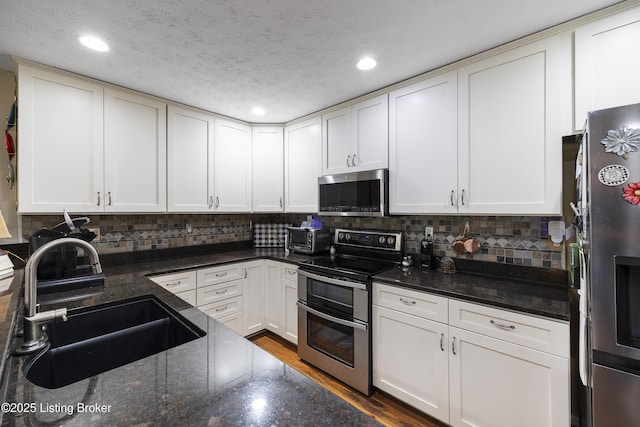 12582 Springfalls Ct, Louisville, KY 40229 - kitchen featuring stainless steel appliances, recessed lighting, tasteful backsplash, dark stone counters, and white cabinetry