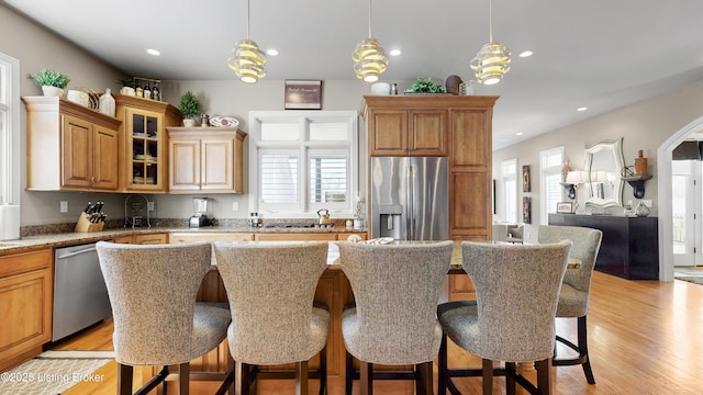 8705 Summit Ridge Dr, Louisville, KY 40241 - kitchen featuring stainless steel appliances, a kitchen bar, light wood-style floors, glass insert cabinets, and pendant lighting