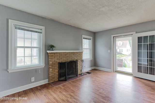 3019 Wirth Ave, Louisville, KY 40217 - unfurnished living room featuring a textured ceiling, a brick fireplace, and wood finished floors