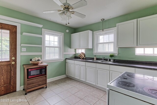 3019 Wirth Ave, Louisville, KY 40217 - kitchen with black microwave, electric stove, dark countertops, white cabinetry, and plenty of natural light