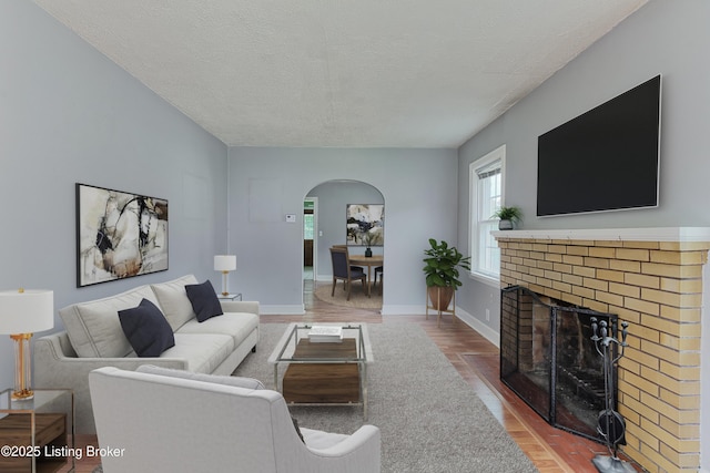3019 Wirth Ave, Louisville, KY 40217 - living area featuring arched walkways, wood finished floors, a textured ceiling, and a brick fireplace