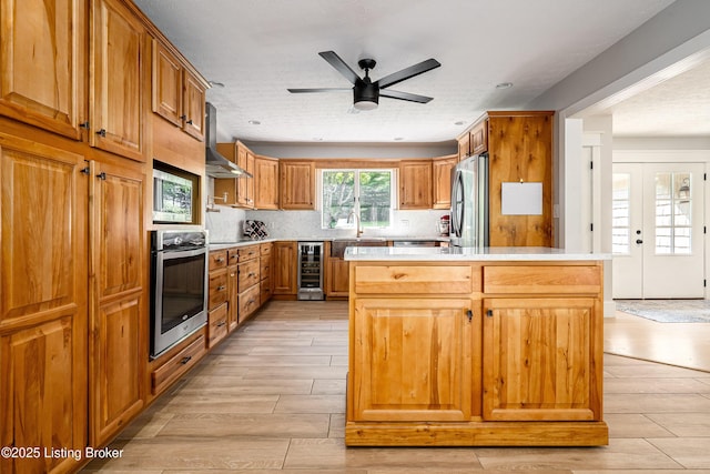 2918 Spickert Knob Rd, Floyds Knobs, IN 47119 - kitchen with stainless steel appliances, beverage cooler, wall chimney range hood, light countertops, and brown cabinetry