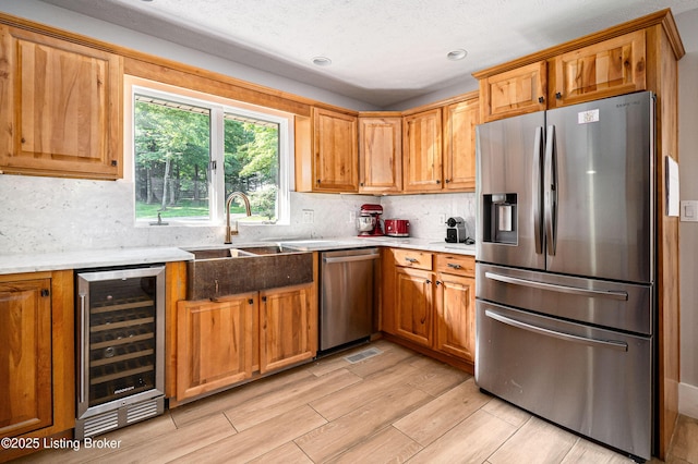 2918 Spickert Knob Rd, Floyds Knobs, IN 47119 - kitchen with stainless steel appliances, beverage cooler, backsplash, light wood-type flooring, and brown cabinets