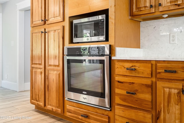2918 Spickert Knob Rd, Floyds Knobs, IN 47119 - kitchen with stainless steel appliances, light countertops, brown cabinetry, and light wood-style floors
