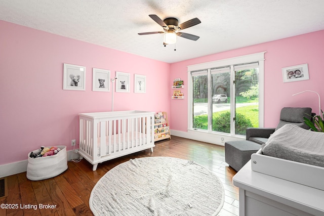 2918 Spickert Knob Rd, Floyds Knobs, IN 47119 - bedroom with hardwood / wood-style flooring, a nursery area, a ceiling fan, and a textured ceiling