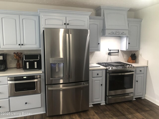 149 Wood Gate Dr, Mt Washington, KY 40047 - kitchen with stainless steel appliances, wall chimney exhaust hood, light countertops, and dark wood finished floors