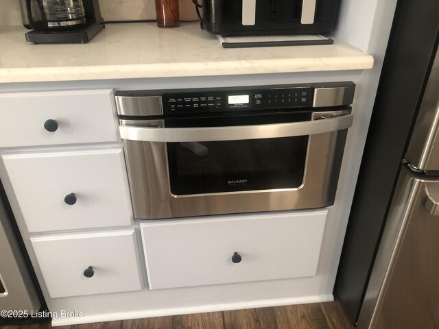 149 Wood Gate Dr, Mt Washington, KY 40047 - detailed view of appliances with stainless steel finishes, white cabinetry, light countertops, and wood finished floors