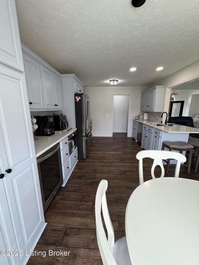 149 Wood Gate Dr, Mt Washington, KY 40047 - kitchen featuring stainless steel appliances, light countertops, dark wood-style flooring, recessed lighting, and a peninsula