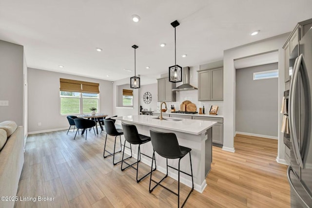 19136 Catalpa Fields Pl, Louisville, KY 40023 - kitchen with gray cabinets, wall chimney exhaust hood, light countertops, a kitchen breakfast bar, and gas cooktop