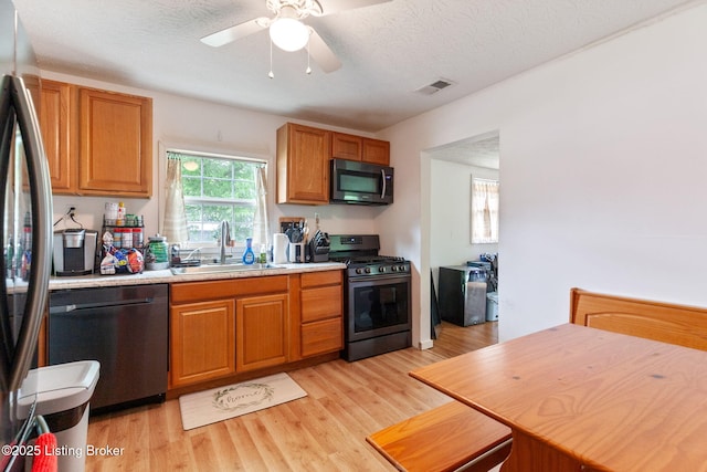 703 Cheri Way, Fairdale, KY 40118 - kitchen featuring appliances with stainless steel finishes, light wood-type flooring, light countertops, brown cabinets, and a textured ceiling