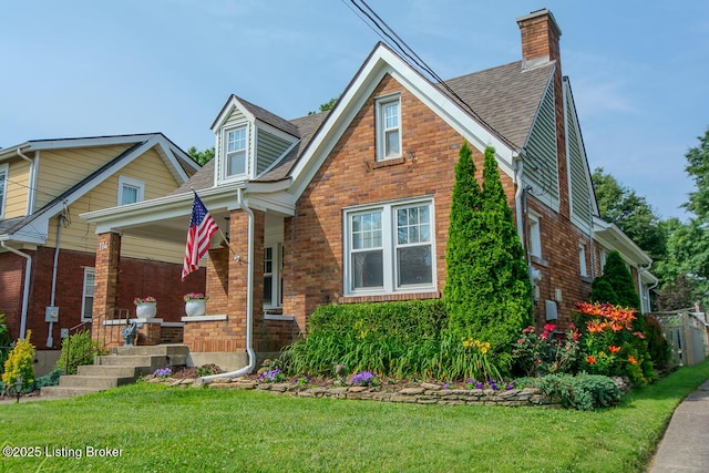 114 S Crestmoor Ave, Louisville, KY 40206 - tudor-style house with a chimney, covered porch, a front yard, and brick siding