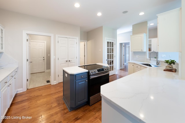 6205 Elizabeth Ct, Prospect, KY 40059 - kitchen with stainless steel electric range oven, light wood-style flooring, white cabinets, a kitchen island, and light stone countertops