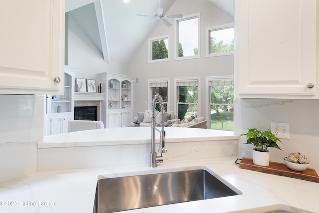 6205 Elizabeth Ct, Prospect, KY 40059 - kitchen featuring open floor plan, high vaulted ceiling, a ceiling fan, a tiled fireplace, and white cabinets