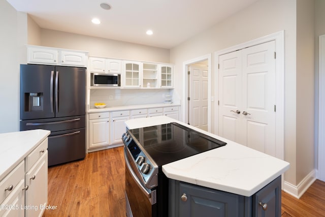 6205 Elizabeth Ct, Prospect, KY 40059 - kitchen with stainless steel appliances, light wood-style floors, white cabinetry, glass insert cabinets, and a kitchen island