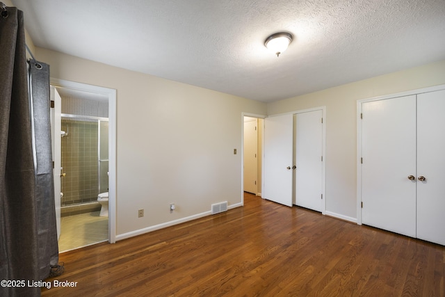 6704 Hollow Tree Rd, Louisville, KY 40228 - unfurnished bedroom featuring multiple closets, wood finished floors, connected bathroom, and a textured ceiling