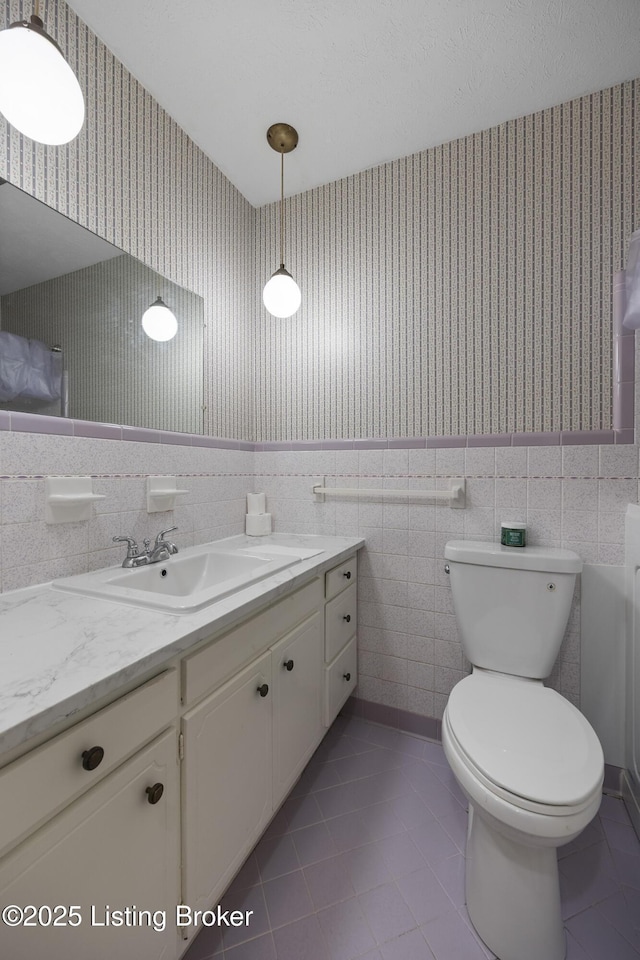 6704 Hollow Tree Rd, Louisville, KY 40228 - bathroom with wallpapered walls, vanity, tile walls, tile patterned flooring, and wainscoting