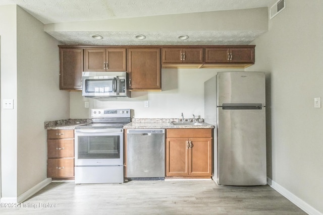 1796 Mellwood Ave, Louisville, KY 40206 - kitchen with appliances with stainless steel finishes, light wood-style flooring, and brown cabinets
