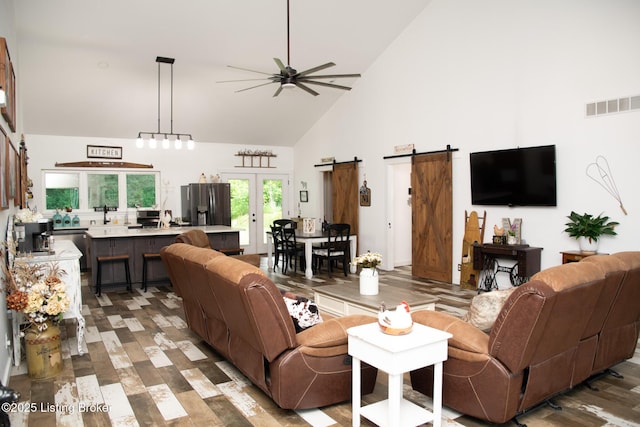 9115 Independence School Rd, Louisville, KY 40228 - living room featuring high vaulted ceiling, a ceiling fan, a barn door, wood finished floors, and french doors