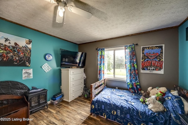 94 Buckhorn Ln, Leitchfield, KY 42754 - bedroom with wood finished floors, a textured ceiling, a wood stove, ceiling fan, and ornamental molding